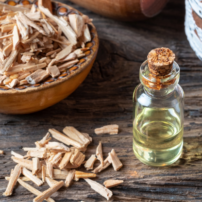 Detox Bath Salts glass bottle with cork stopper filled with oil, and cedarwood chips next to it, on dark wood surface