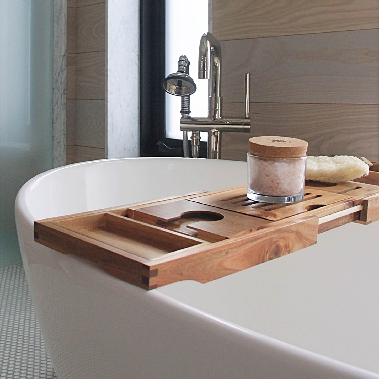 PMS Bath Salts product glass jar filled with Himalayan Crystal Salt, cork cover  resting on wooden tray with slats and candle holder groove resting on white tub in bathroom with window