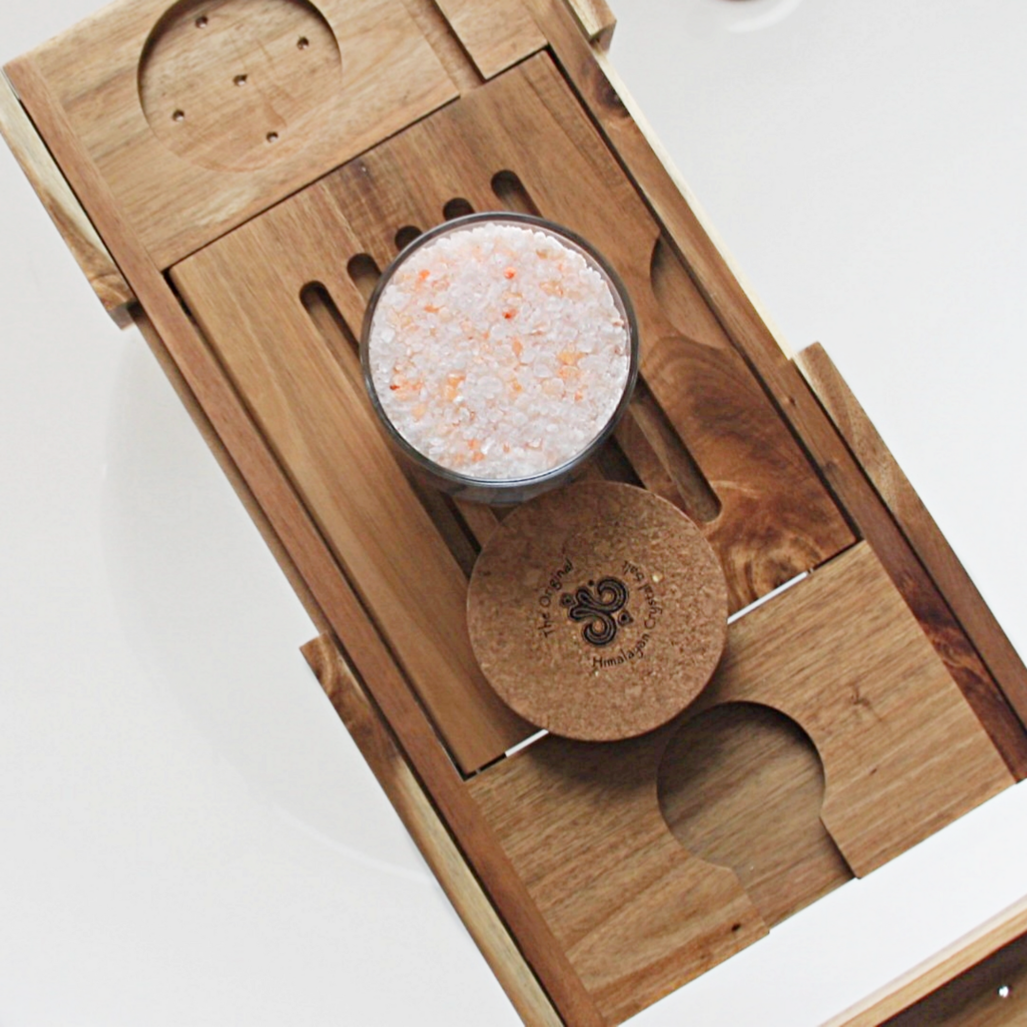 Detox Bath Salts product glass jar filled with Himalayan Crystal Salt stones with salts, cork cover  resting on wooden tray with slats and candle holder groove resting on white tub