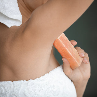 white woman wearing towel on head and body, holding soap bar against arm pit