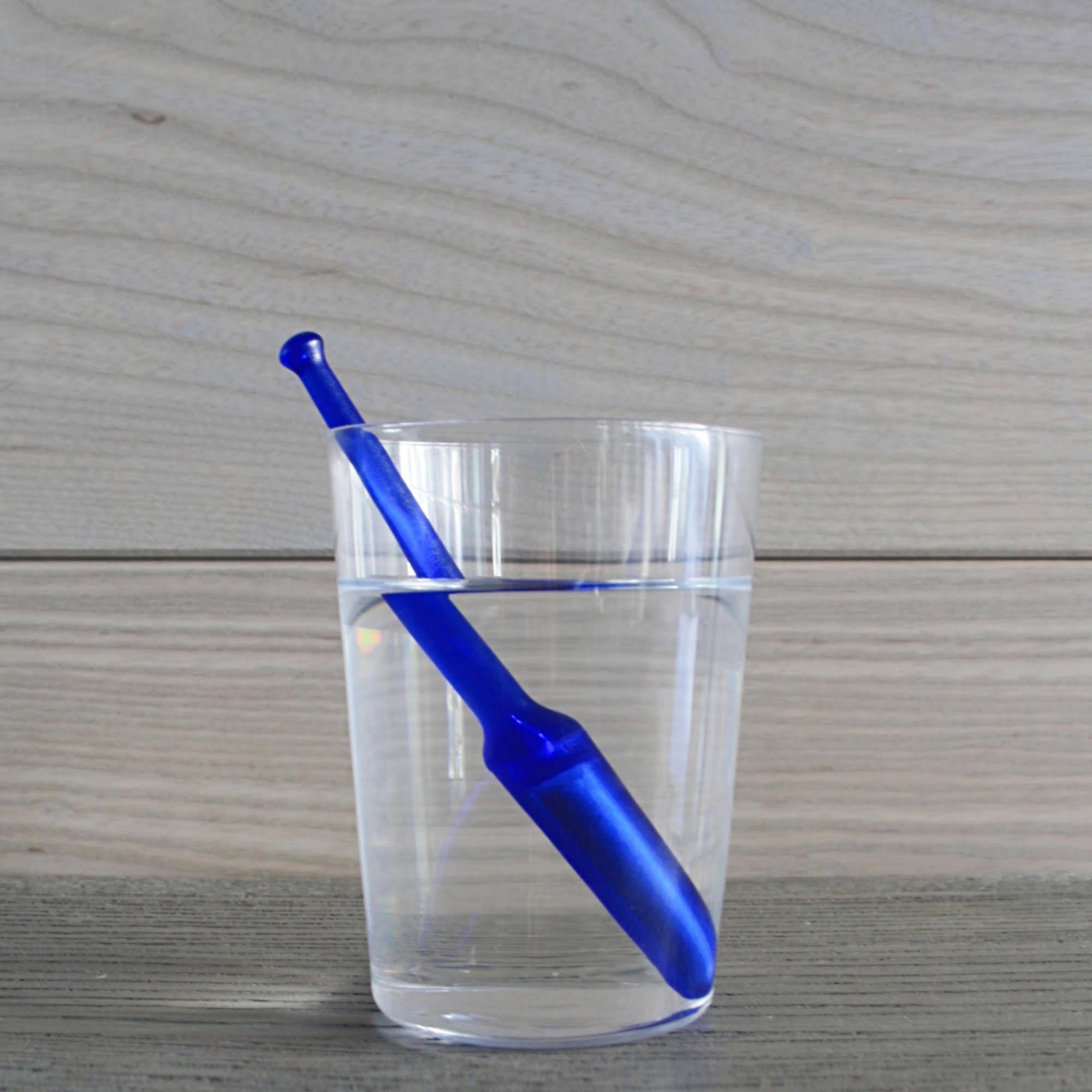 24/7 StirWand blue stirwand in glass filled with water, on wood surface