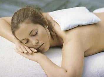 Salt Sachet white woman with brown hair, lying face down with eyes closed on spa table, small white square pillow on back 